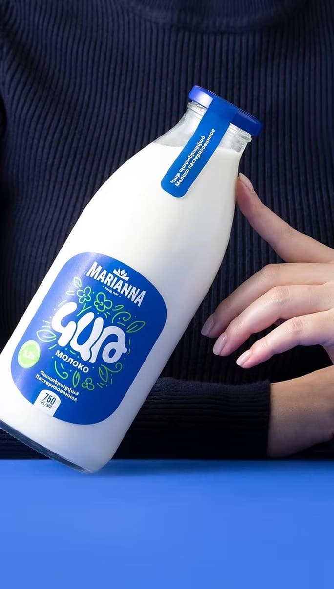 Marianna milk bottle held against a blue background